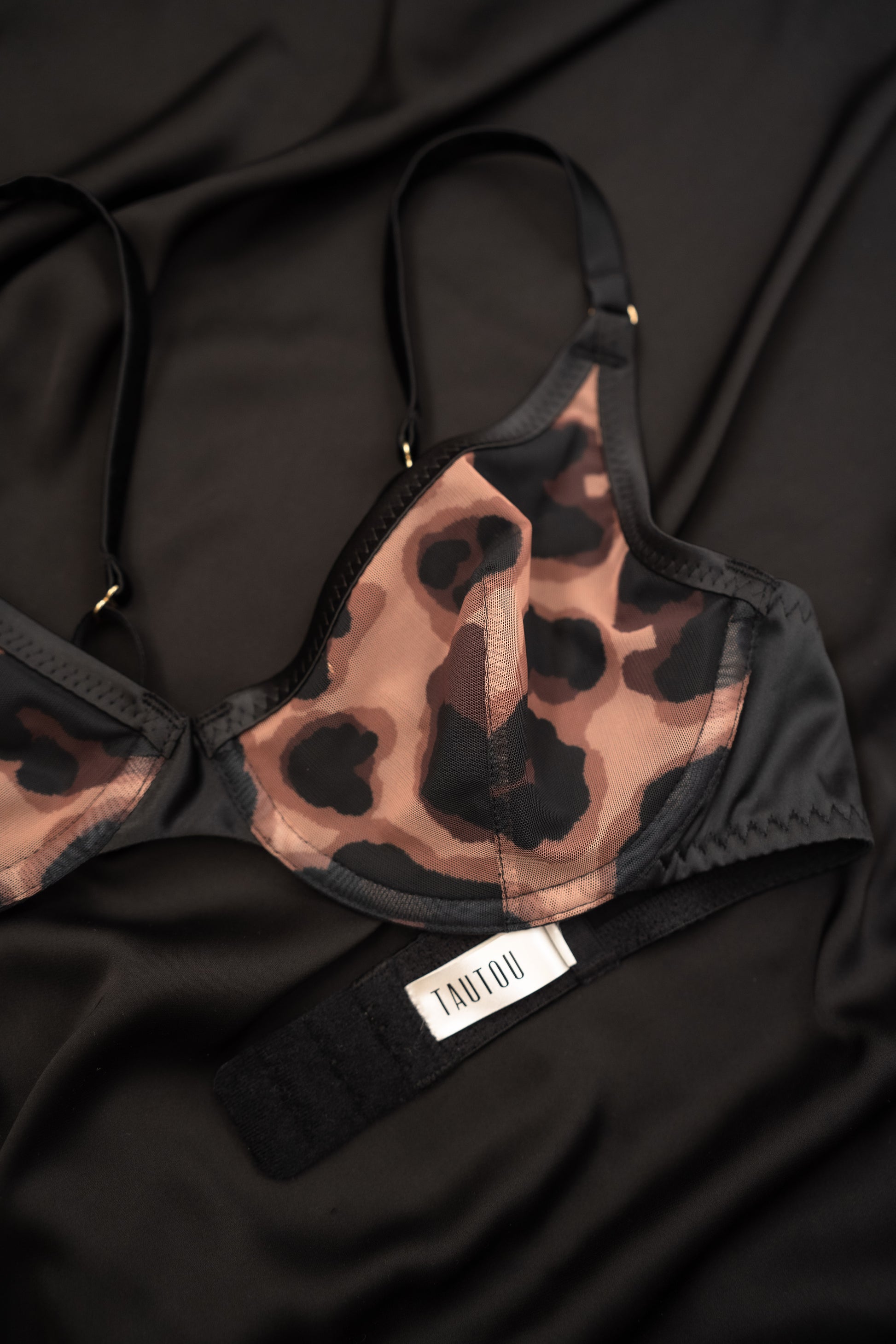 Leopard print Oona bralette on a black fabric background with a visible brand label.