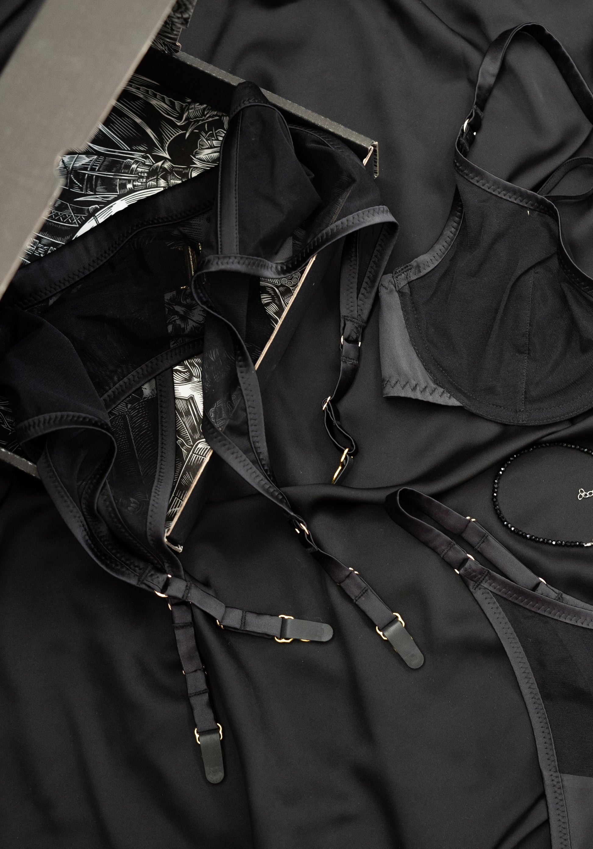 Black striped lingerie set with various straps and buckles on a dark background