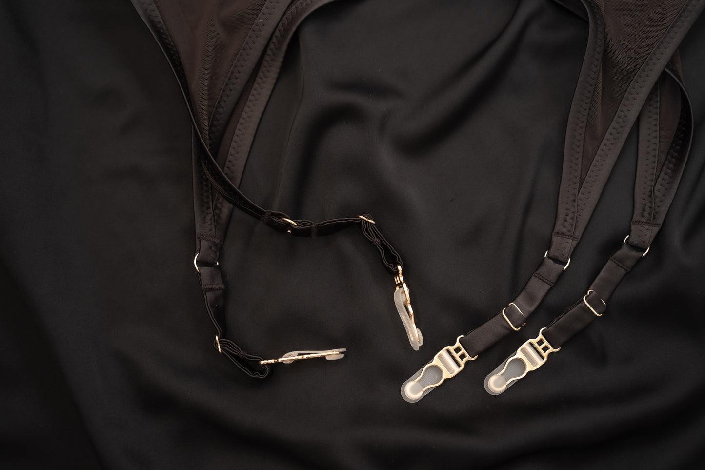 Black suspenders Tate Chocolate lingerie set with gold clasps on a black fabric background
