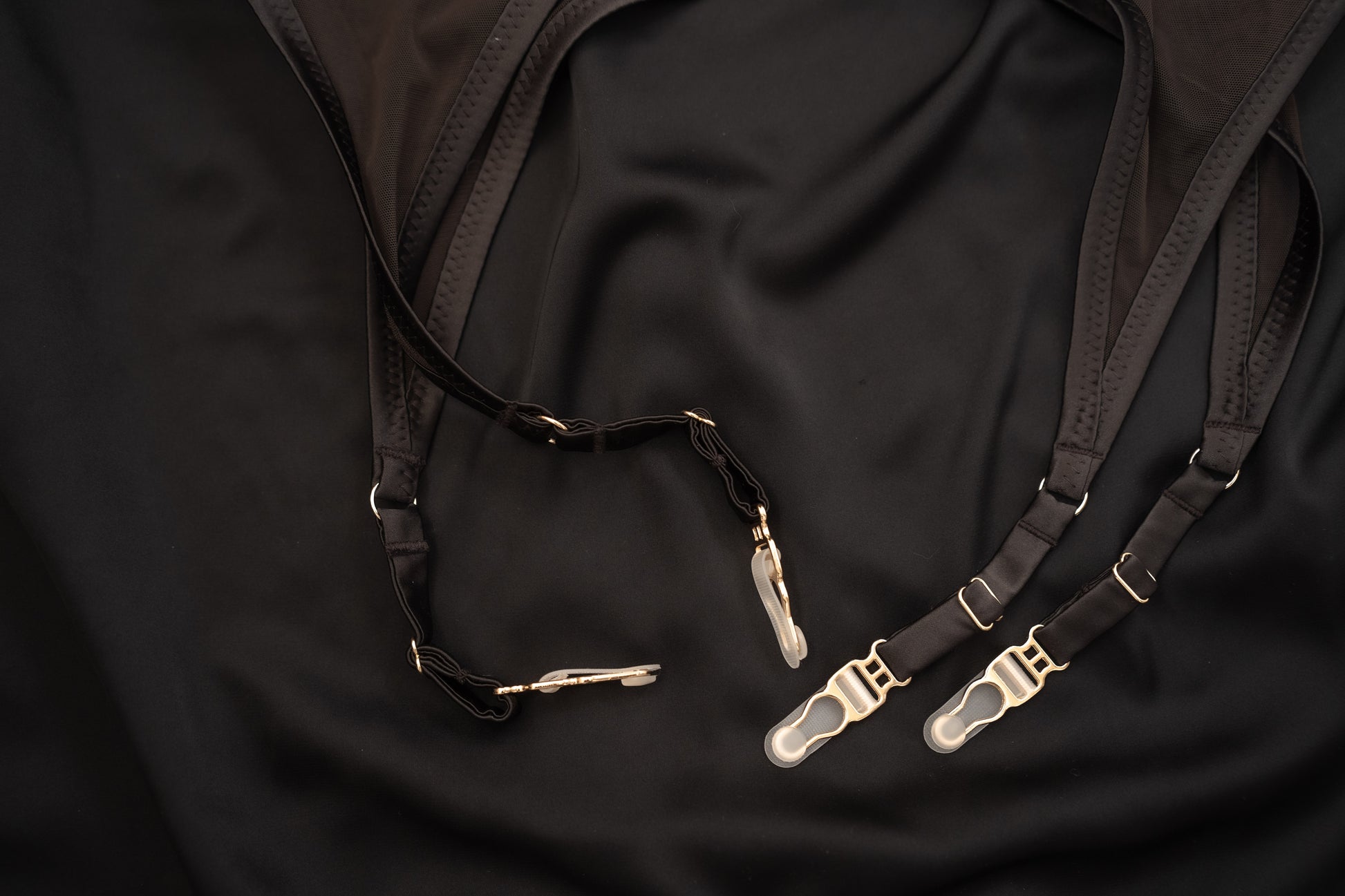 Black suspenders Tate Chocolate lingerie set with gold clasps on a black fabric background